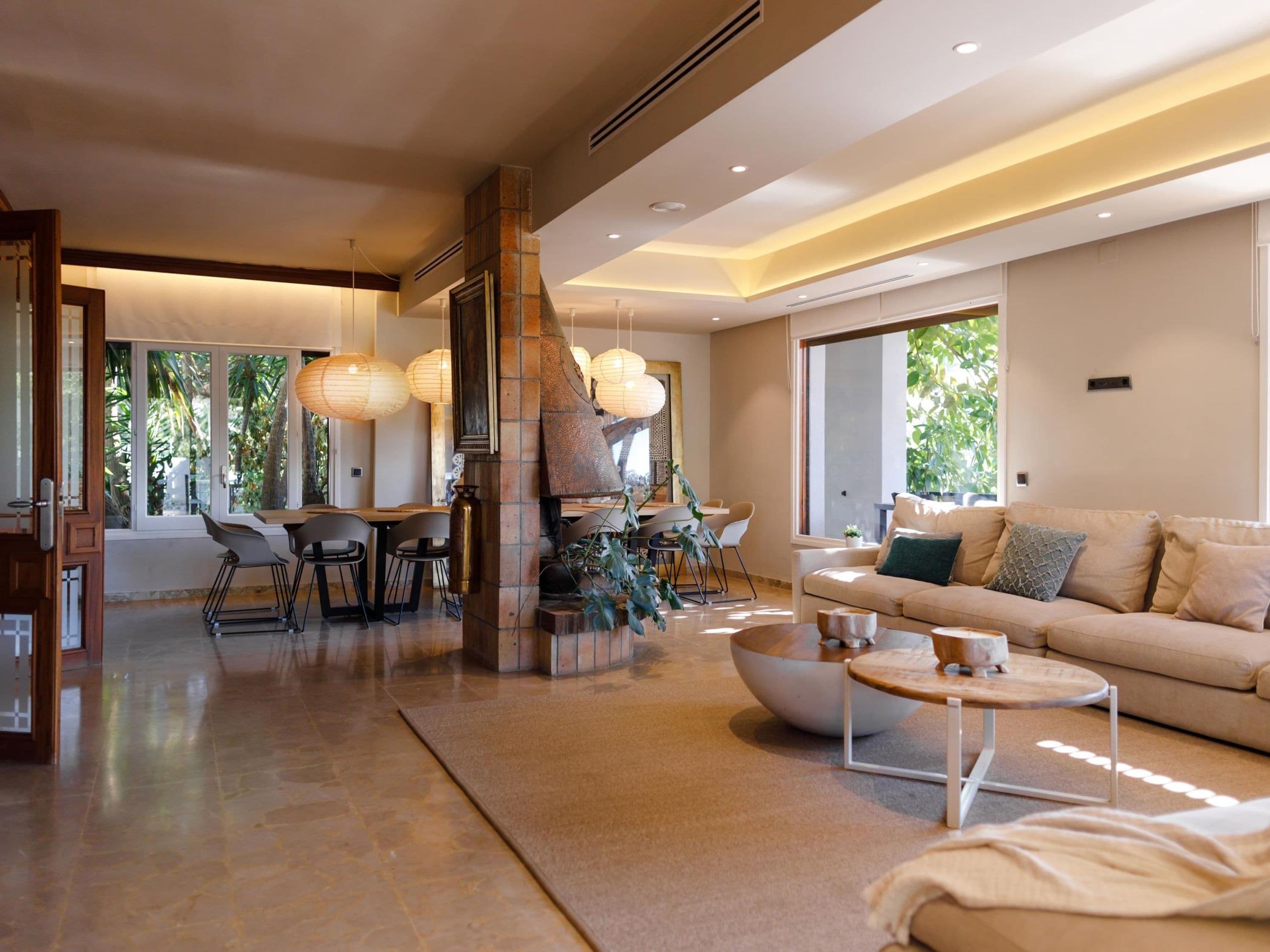 A spacious living area with a modern fireplace, a dining area with chairs and a table, and a comfortable sofa with cushions.