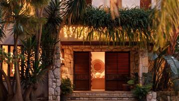 A building with a stone facade, wooden shutters, and a circular decorative element above the entrance.