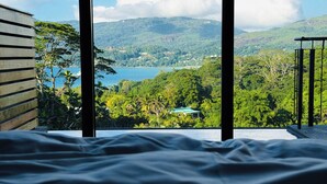 A bedroom with a view of a mountainous landscape and a body of water.