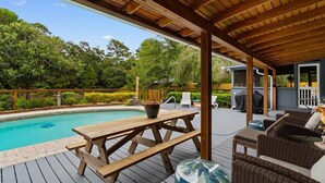 A wooden deck with a pool, outdoor furniture, and a covered area with a grill. - 3 Bedroom Vacation Home with Salt Water Pool (Pawleys Island)
