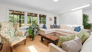 A spacious living room with a white sofa set, a floral armchair, and a wooden coffee table. - 3 Bedroom Vacation Home with Salt Water Pool (Pawleys Island)
