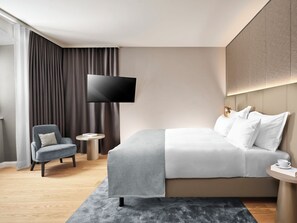 A modern hotel room with a bed, a TV, a chair, and a small table. - Nature Resort Jakobsberg (Boppard)