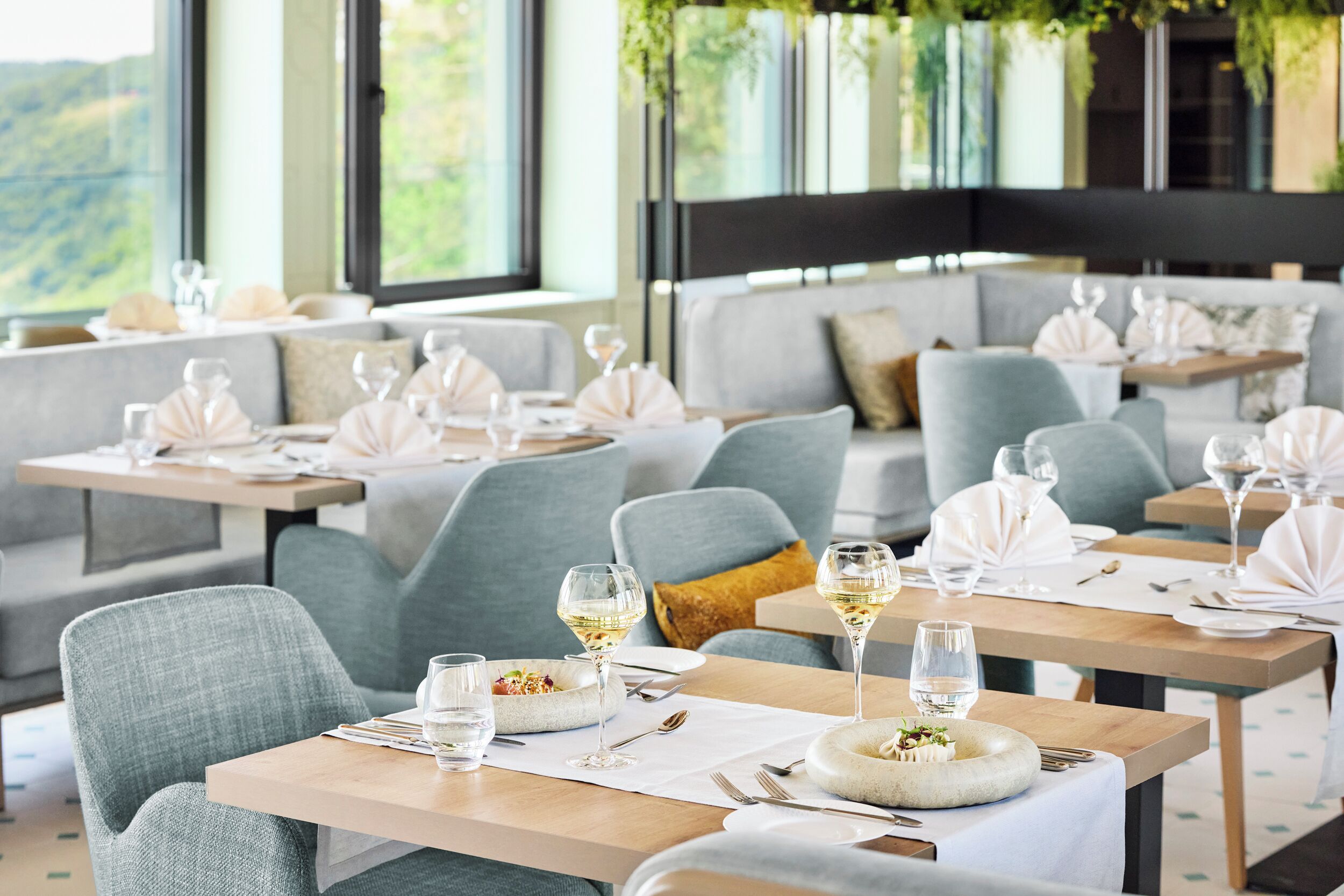 A restaurant with multiple tables set for dining, each with a bowl of salad and a glass of water.