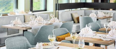 A restaurant with multiple tables set for dining, each with a bowl of salad and a glass of water.