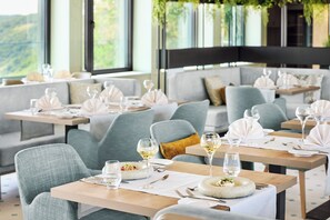 A restaurant with multiple tables set for dining, each with a bowl of salad and a glass of water. - Nature Resort Jakobsberg (Boppard)