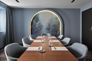 Un salón de conferencias con una mesa larga, seis sillas y un amplio ventanal con vista al bosque.