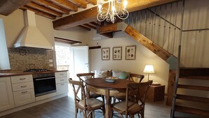 A dining area with a wooden table and chairs, a chandelier, and a staircase. - Casina Laura (Capannori)