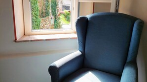 A room with a window, a blue chair, and a tiled floor. - Casina Laura (Capannori)