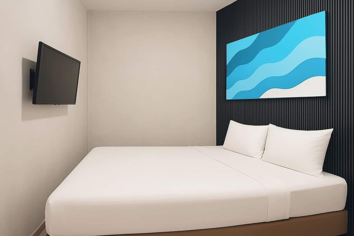 Ein modernes Hotelzimmer mit einem an der Wand befestigten Flachbildfernseher, einem Bett mit weißer Bettwäsche und einem großen abstrakten Gemälde darüber.