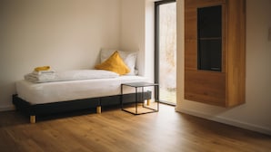 Une chambre à coucher moderne avec un lit, une petite table de chevet et une armoire en bois.