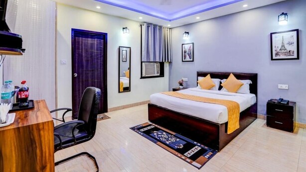A modern hotel room with a large bed, a desk, and a chair. - Hotel maayra inn (Noida)