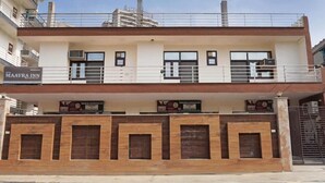 A two-story building with a flat roof, a balcony on the upper floor, and a gated entrance. - Hotel maayra inn (Noida)