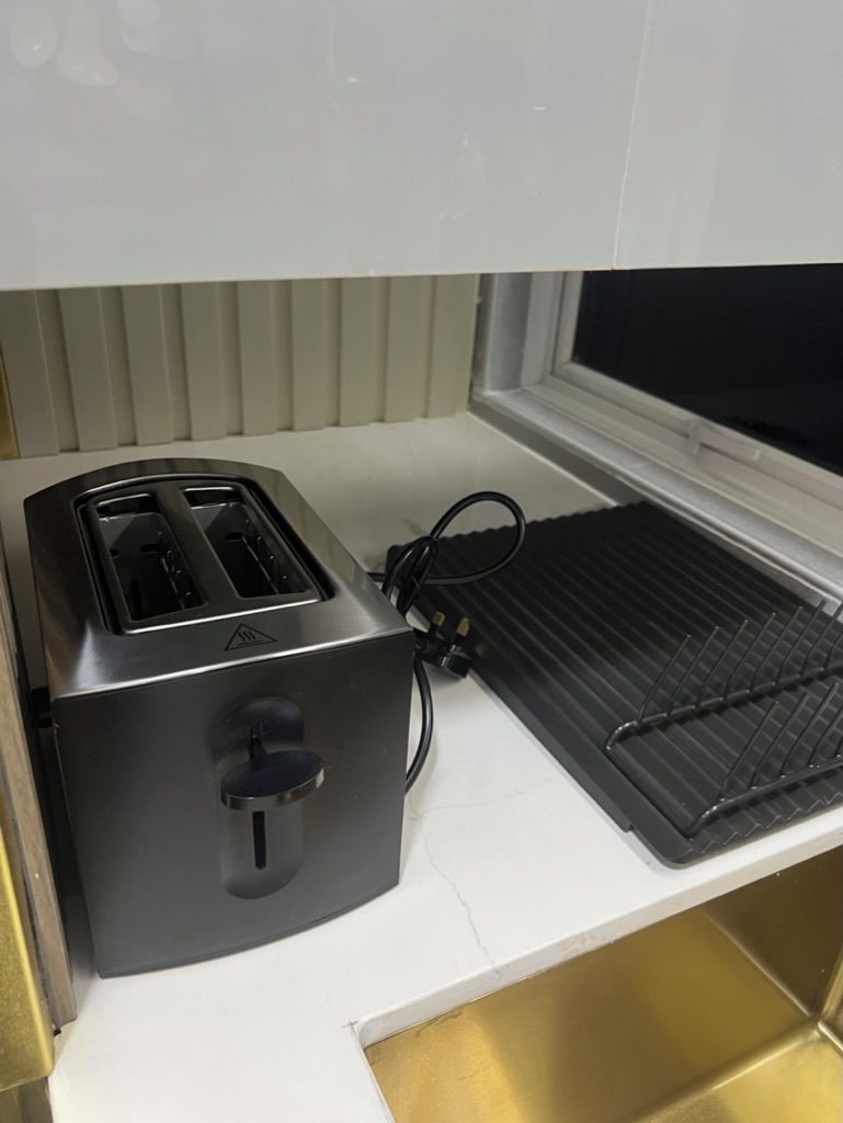 Una cocina con un tostador, una tetera y un lavabo.
