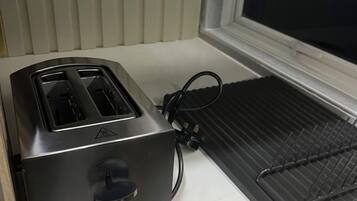 Una cocina con un tostador, una tetera y un lavabo.