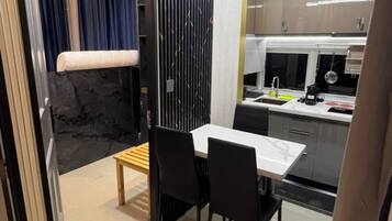 Una cocina compacta con electrodomésticos modernos, un comedor con mesa y sillas, y vistas de la habitación contigua.