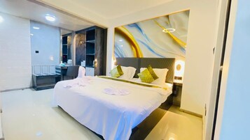 Une chambre d’hôtel avec un grand lit, un bureau et une chaise. Un mur est décoré d’un motif ornemental et un luminaire est fixé au plafond.