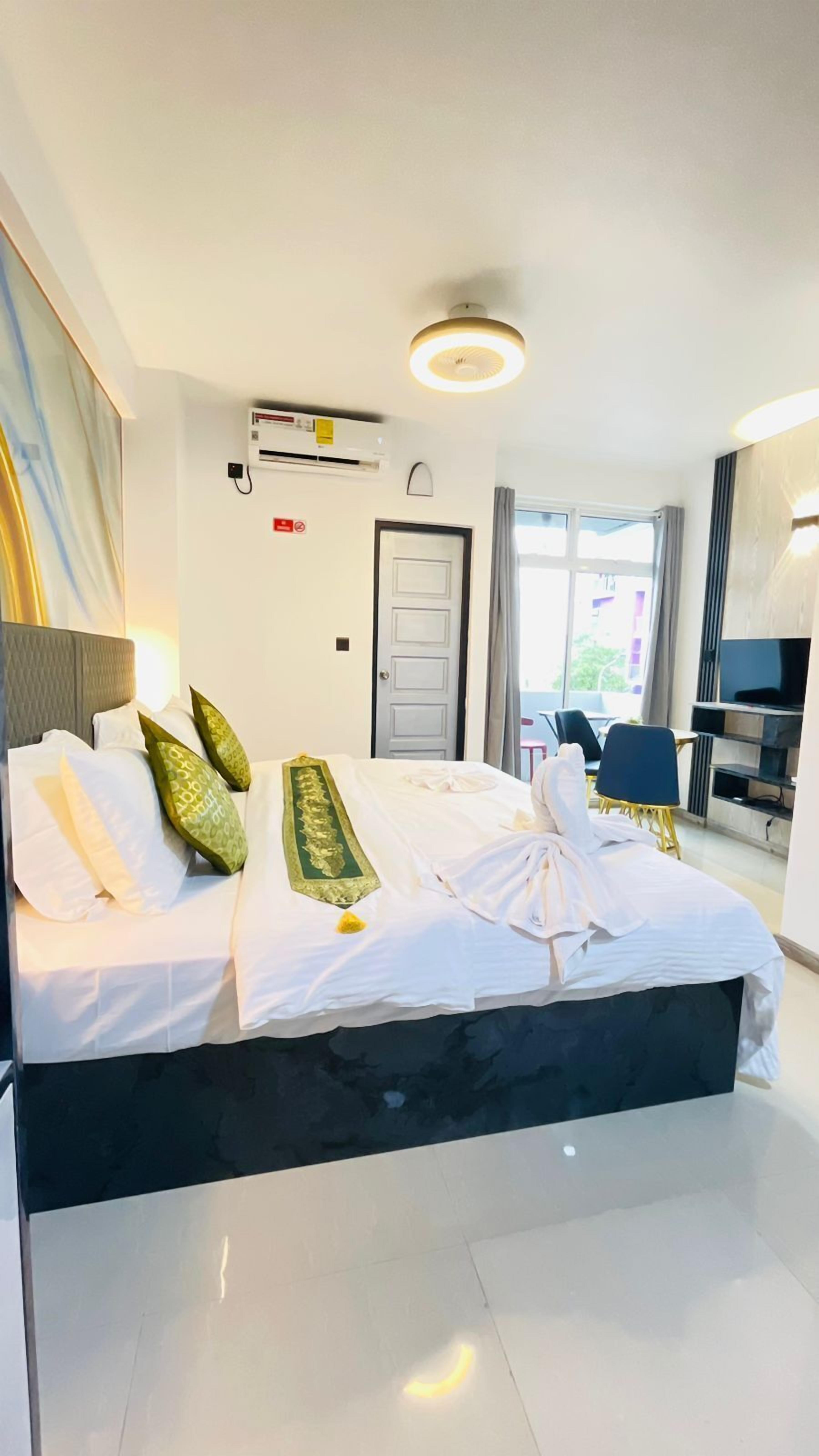 A hotel room with a bed, a TV, a desk, and a window.