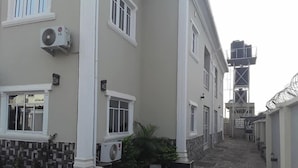 Un bâtiment doté de nombreuses fenêtres, de climatiseurs et d’un chemin bordé de carreaux.