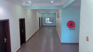 Un couloir doté d’un plancher poli, une porte sur le côté gauche et un objet circulaire rouge sur le mur de droite.