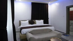 Une chambre d’hôtel moderne, équipée d’un lit, d’une petite table ronde et offrant une vue sur l’extérieur.