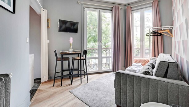A modern room with a sofa, a TV, a dining area with chairs, and a balcony with curtains. - Peaceful Studio - 2P -near the Canal Saint-martin (Paris)