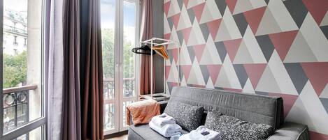 A modern room with a grey sofa, patterned cushions, and a geometric wall design.