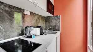 A modern kitchen with a black induction cooktop, a coffee maker, and a kettle. - Peaceful Studio - 2P -near the Canal Saint-martin (Paris)