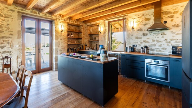 A rustic kitchen with wooden beams, stone walls, a central island, and modern appliances. - Villa 'Le Basque' in Bazas with Shared Pool, Private Terrace and Wi-Fi (Bazas)