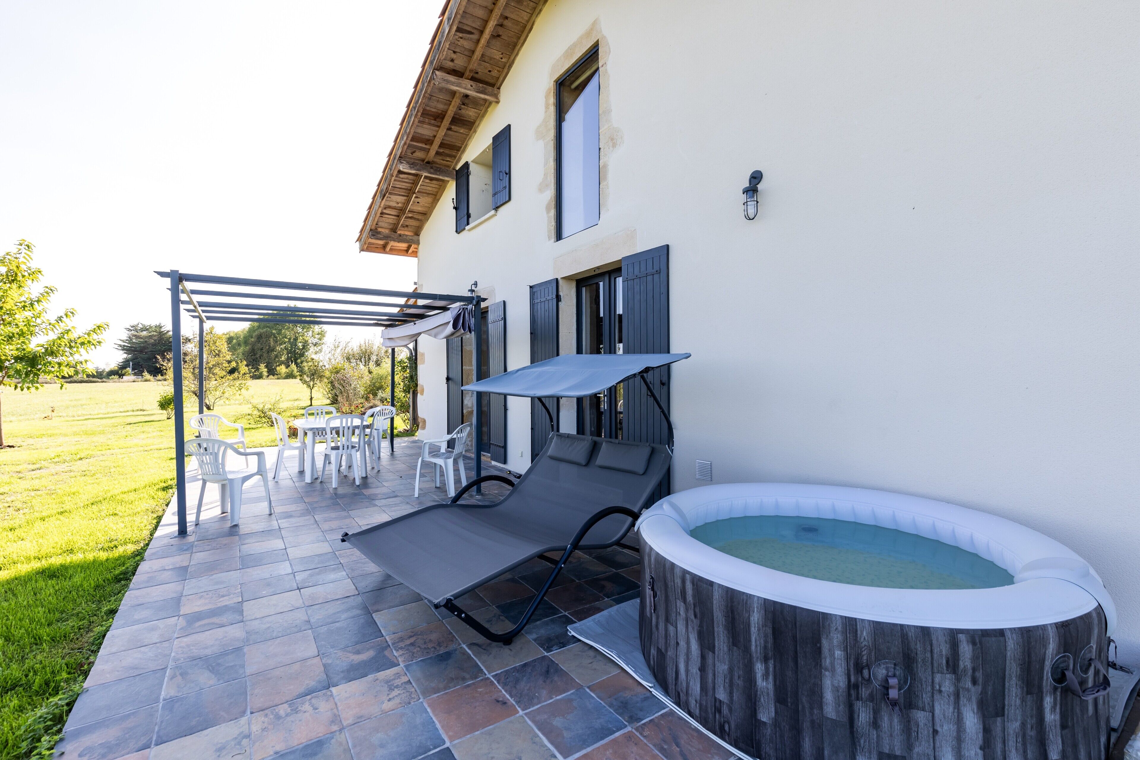 A patio with outdoor furniture, a hot tub, and a pergola.