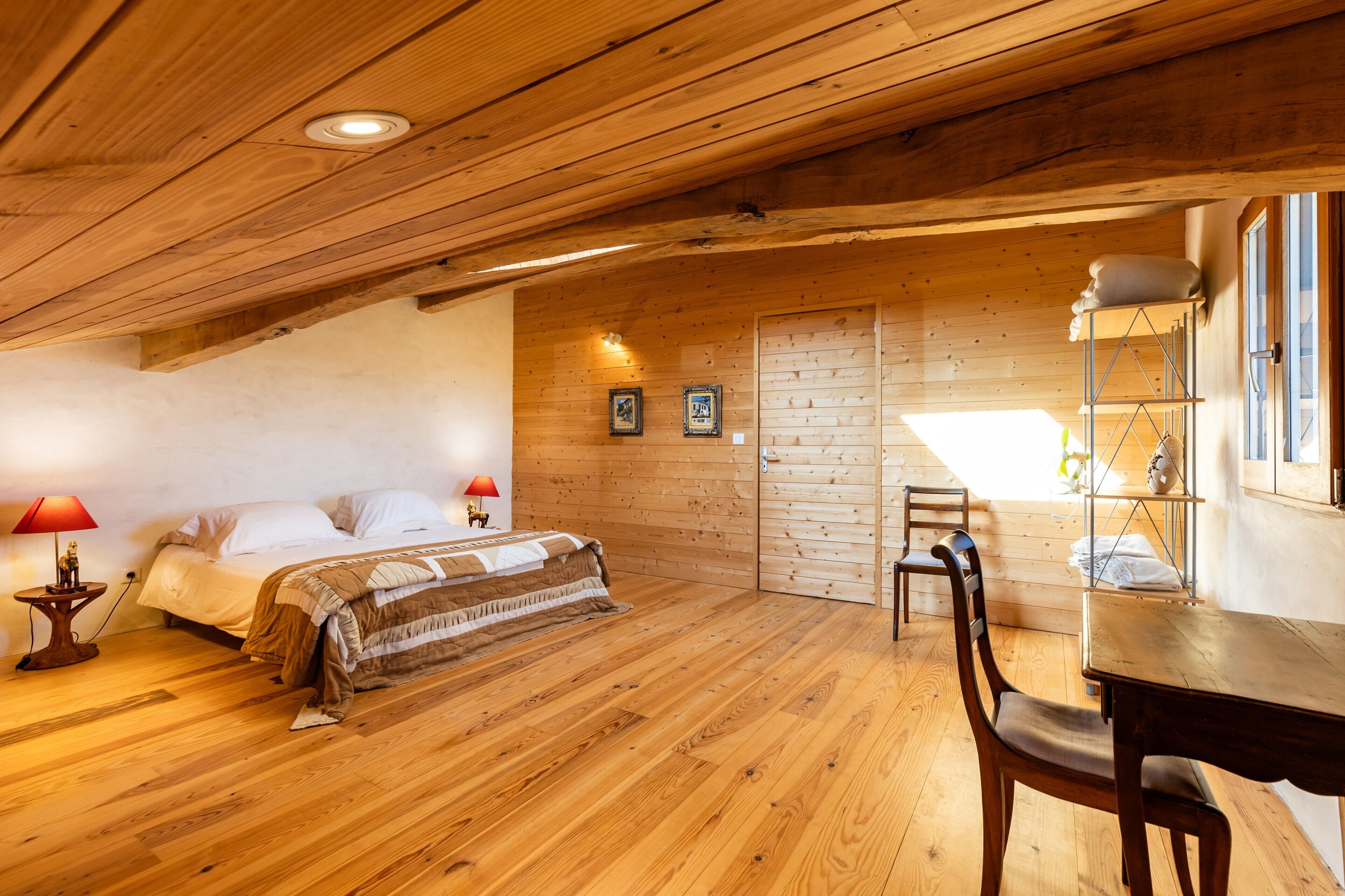 Una stanza in legno con un letto, una scrivania e una sedia.