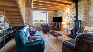 A cozy living room with a sofa, armchairs, a coffee table, a fireplace, a television, and a view of the outdoors. - Villa 'Le Basque' in Bazas with Shared Pool, Private Terrace and Wi-Fi (Bazas)