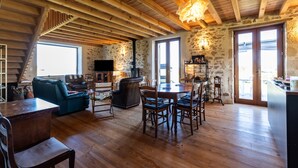 A spacious living area with a wooden ceiling, stone walls, a dining table, and a cozy seating arrangement. - Villa 'Le Basque' in Bazas with Shared Pool, Private Terrace and Wi-Fi (Bazas)
