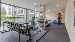 Un gimnasio moderno con un ventanal grande, un espejo y diverso equipo de ejercicios.
