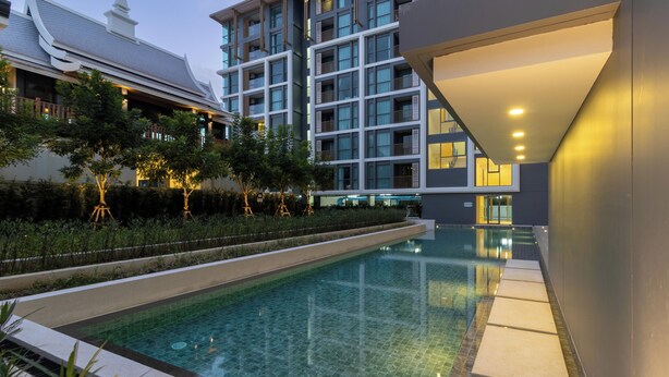 Un hotel moderno con piscina, rodeado de abundante vegetación y arquitectura tradicional.