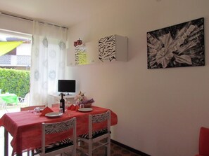 Ein Essbereich mit einem für zwei Personen gedecktem Tisch, einem Fernseher und einer Wand mit abstrakter Kunst.
