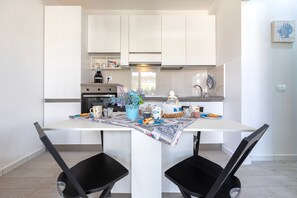 A modern kitchen with white cabinets, a dining table with chairs, and a decorative centerpiece. - Holiday Home 'Marachele' with Shared Pool, Private Garden, and Air Conditioning (Castelsardo)