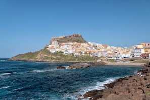 A coastal town with colorful buildings, a rocky shoreline, and a prominent hill with a fort-like structure. - Casa Marachele Vacation Home with Pool, Private Garden, and Air Conditioning (Castelsardo)