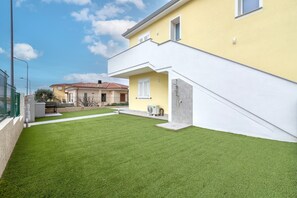 A residential property with a well-maintained lawn, a white exterior, and a visible air conditioning unit. - Holiday Home 'Marachele' with Shared Pool, Private Garden, and Air Conditioning (Castelsardo)
