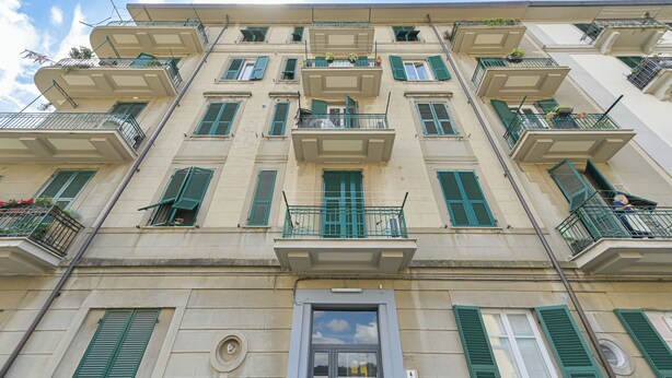 A multi-story building with balconies, a central entrance, and a clear sky. - The Houses on the Park 2 (La Spezia)