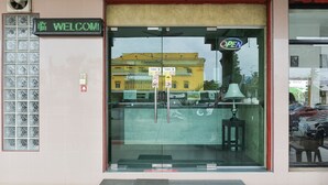 Ein Schaufenster mit einer digitalen Willkommensanzeige, einer Glastür und einem Schild mit der Aufschrift 'OPEN'.