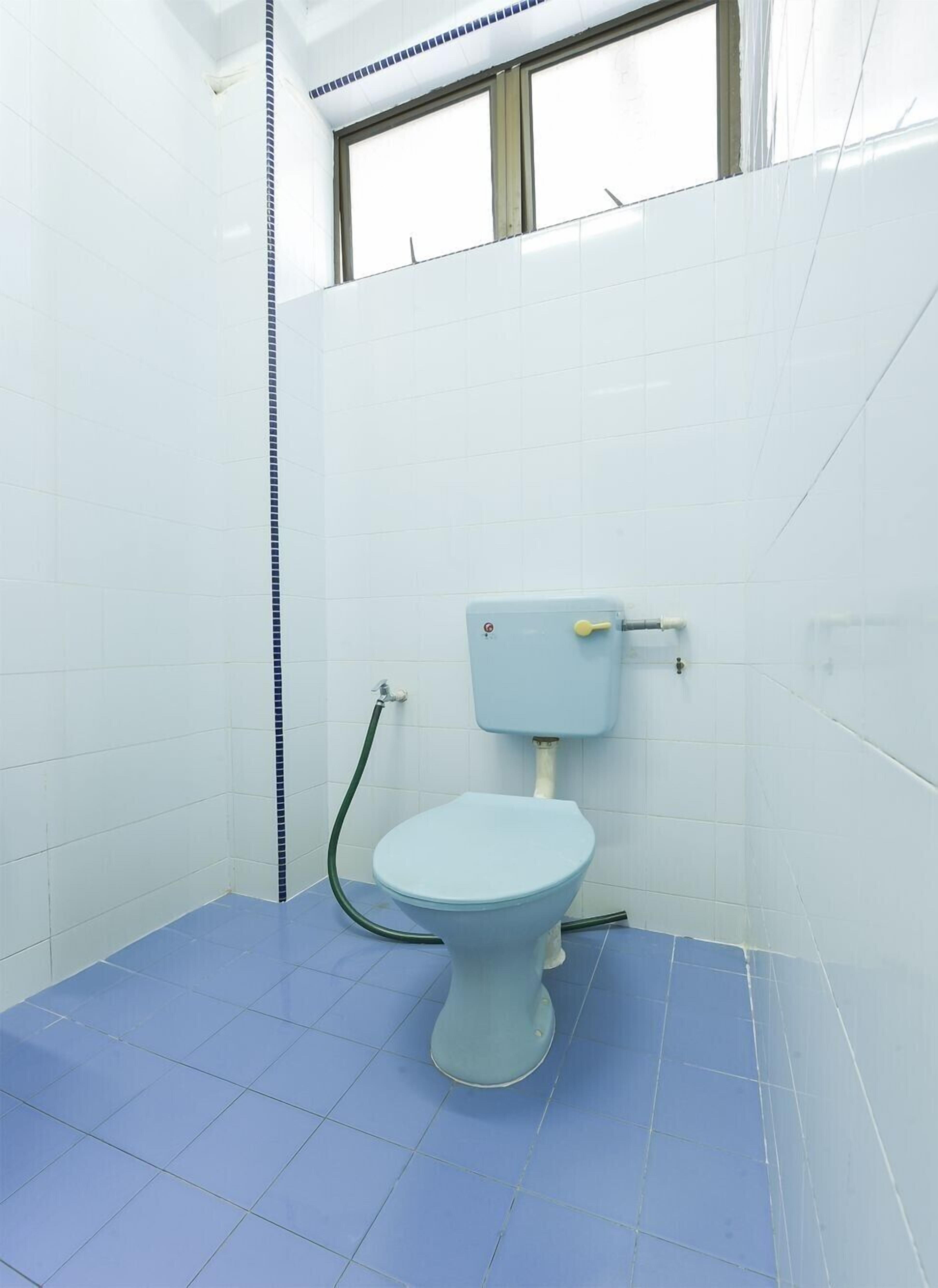 A small bathroom with a toilet, a window, and a blue floor.