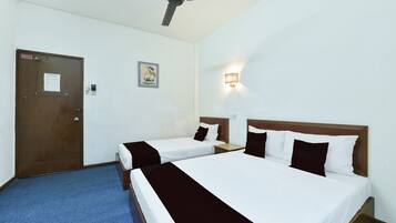 A hotel room with two single beds, a ceiling fan, a door with a sign, and a wall-mounted light fixture.