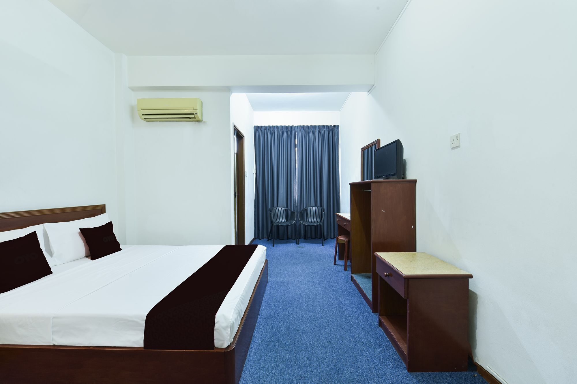 A hotel room with a bed, a desk, a television, and a wardrobe.