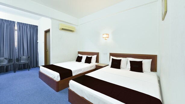 Ein Hotelzimmer mit zwei Betten, einem Schreibtisch, einem Stuhl und einem Vorhangfenster.