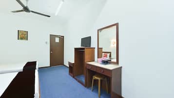 Habitación de hotel con cama, escritorio con silla, televisión, espejo y ventilador de techo.