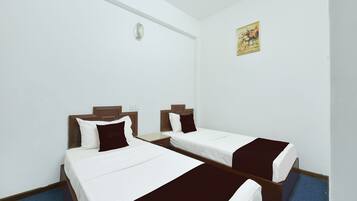 Habitación de hotel con dos camas individuales, cada una con cabecero de madera, ropa de cama blanca y detalles en marrón.
