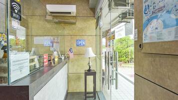 A reception area with a counter, a flag, a lamp, and a sign indicating the entrance is open.