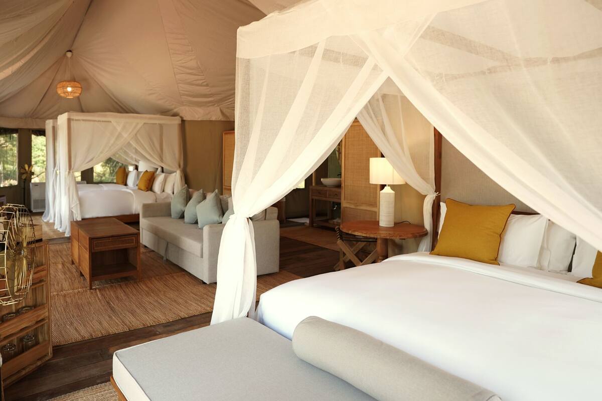 A tent-style bedroom with a bed, a sofa, and a table.