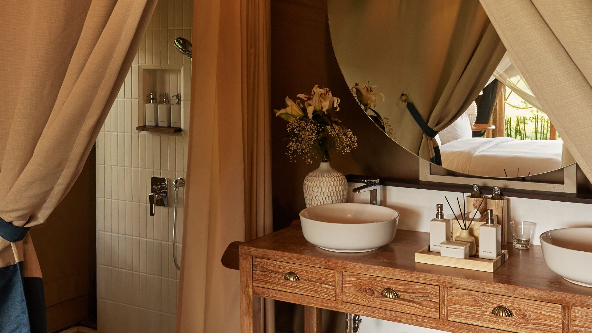 Un baño con tocador de madera, dos lavamanos, un espejo y cabina de ducha.