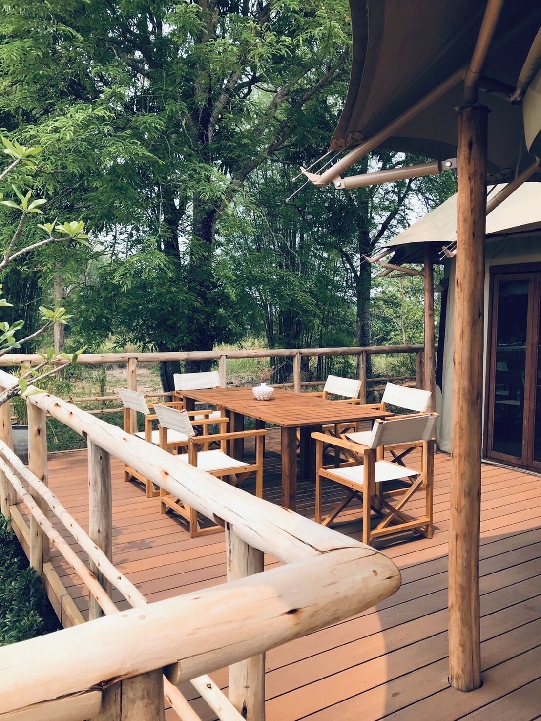 A wooden deck with a table and chairs, surrounded by a wooden railing.